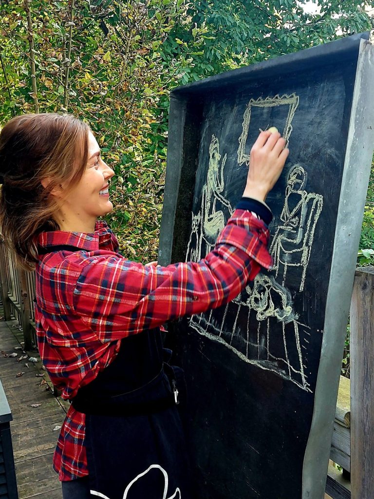 Mary Anne Liam drawing with chalk on a large blackboard outdoors